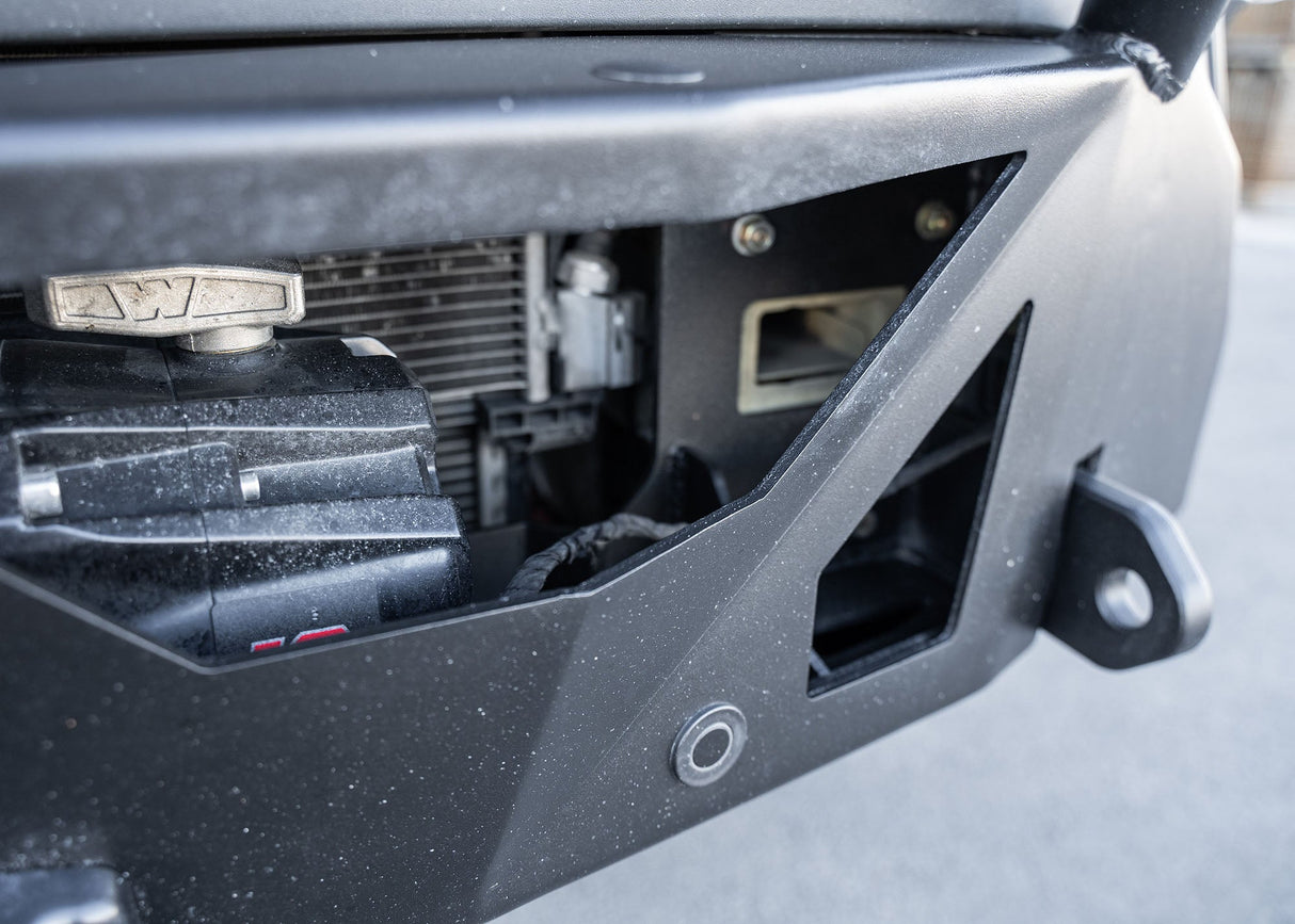Close-up of the ROAMBUILT LoPro Front Bumper on a Mercedes-Benz Sprinter van, featuring a Warn VR-EVO winch with hawse fairlead, integrated parking sensors, and 1-inch thick steel shackle mounts, all encased within a lightweight 5052 aluminum outer shell.