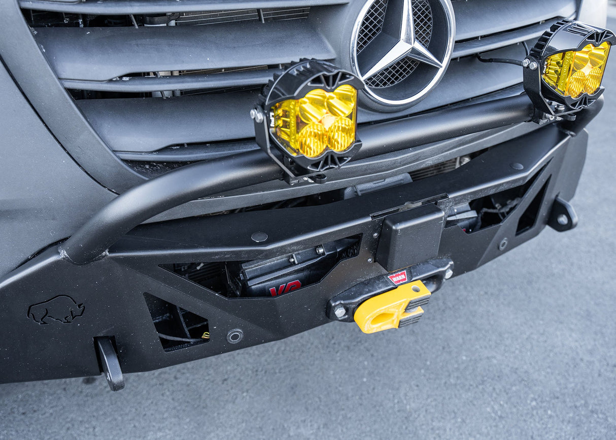 Top-down view of a Mercedes-Benz Sprinter van equipped with the ROAMBUILT LoPro Front Bumper, highlighting integrated parking sensors, Active Brake Assist (ABA) sensor, 1-inch thick steel shackle mounts, and Baja lights mounted on the welded aluminum bull bar, all encased within a lightweight aluminum shell.