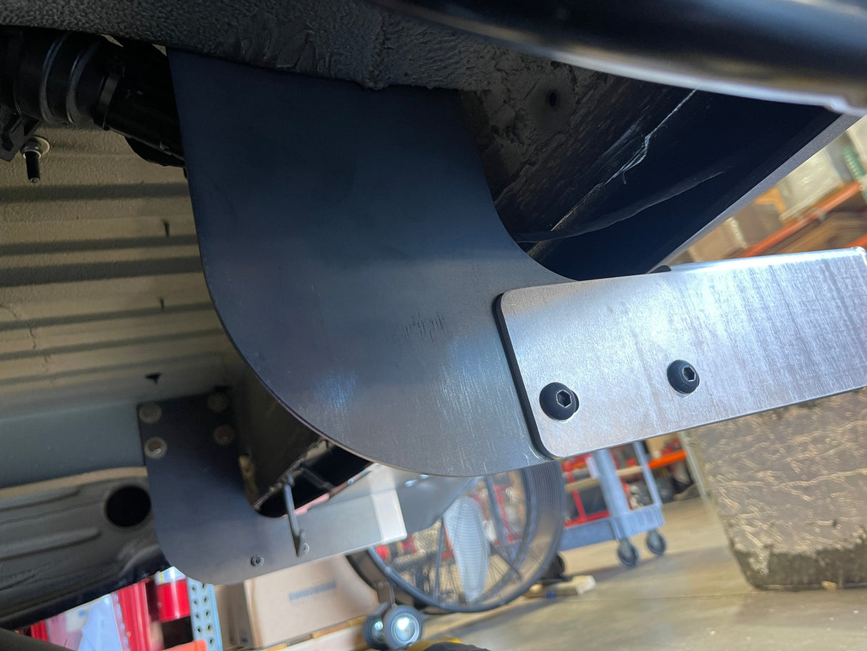 Close-up of a metal component under a vehicle with a blurred background