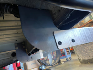 Close-up of a metal component under a vehicle with a blurred background